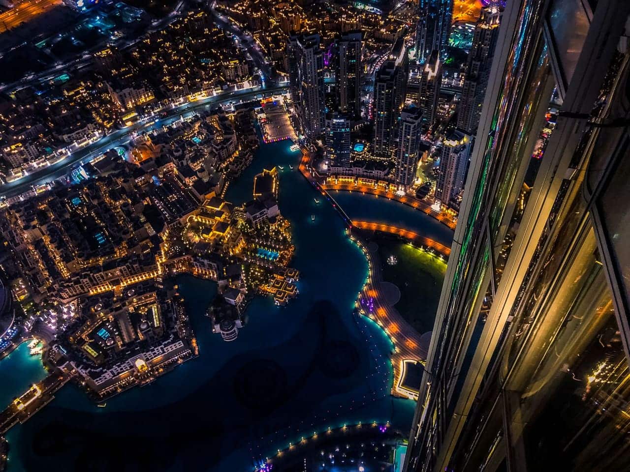 Aerial view of central Dubai at night with city lights below.