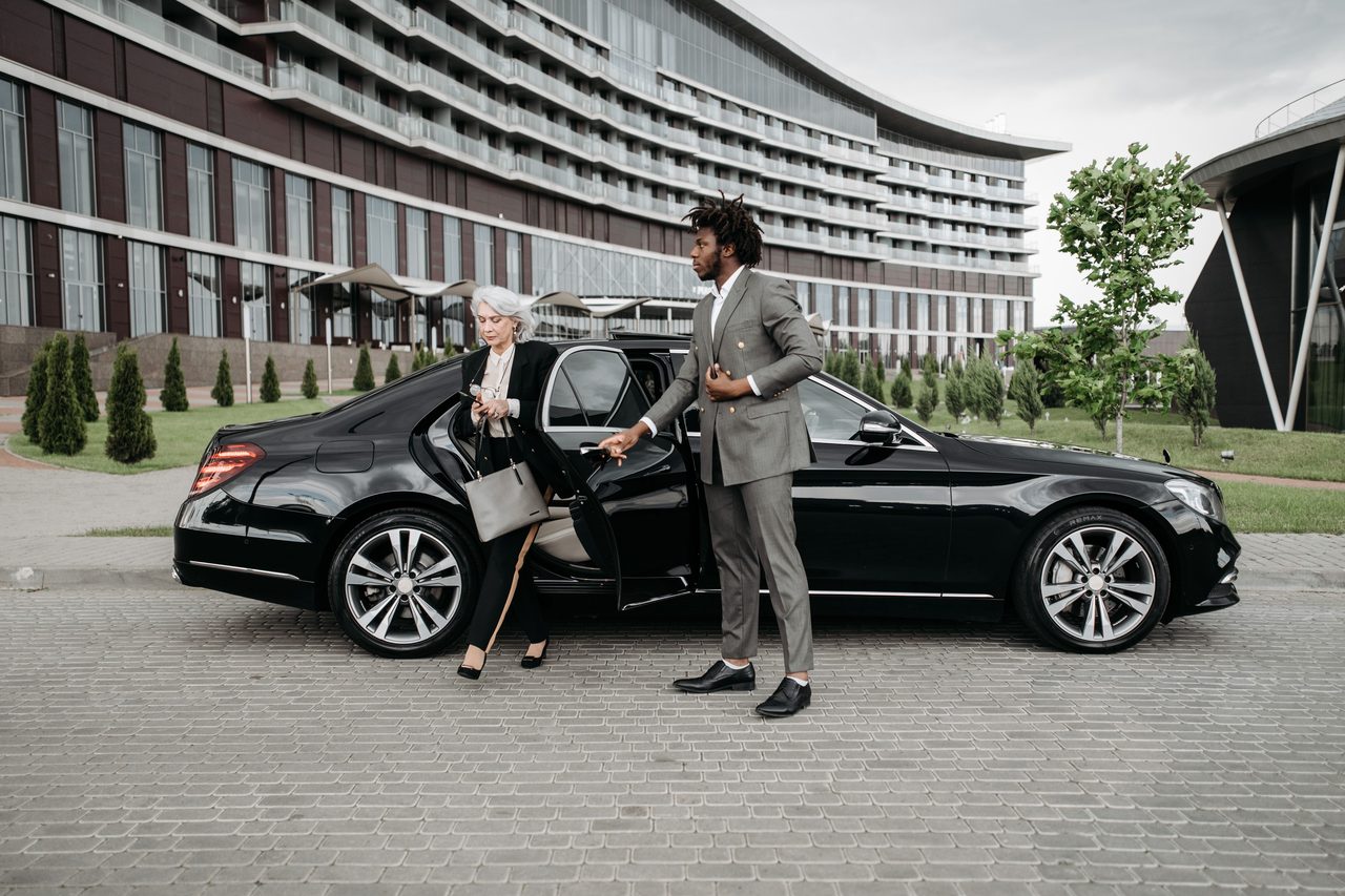An ALVIA host welcoming a guest arriving by private car at a Dubai hotel.