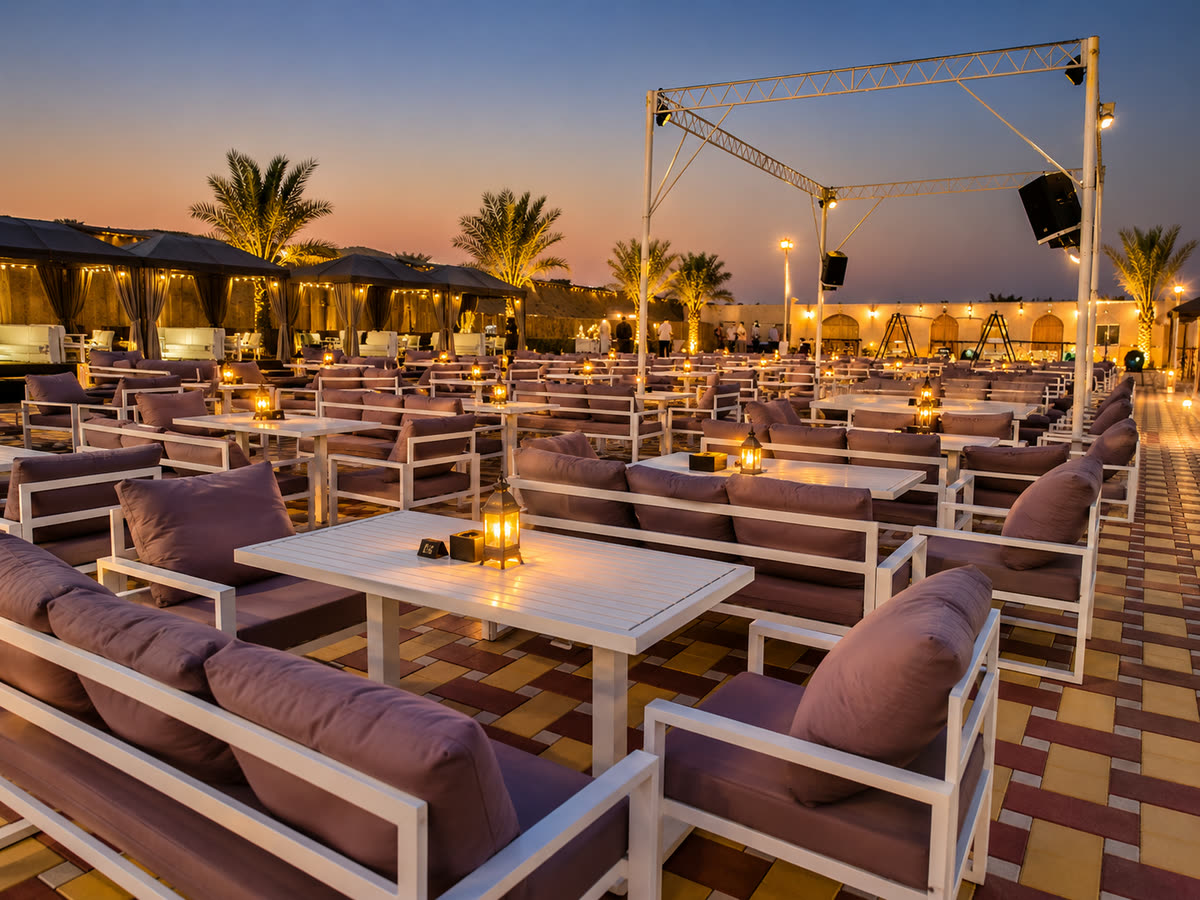 VIP desert camp seating with sofas, low tables and lanterns at dusk