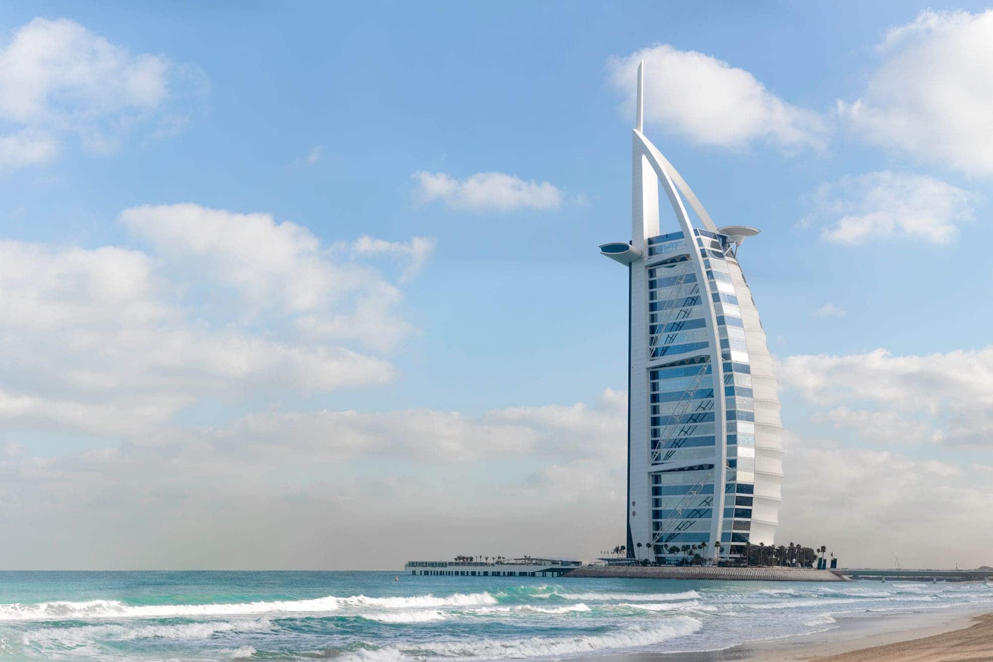The Burj Al Arab hotel on the Jumeirah coastline under a clear Dubai sky.