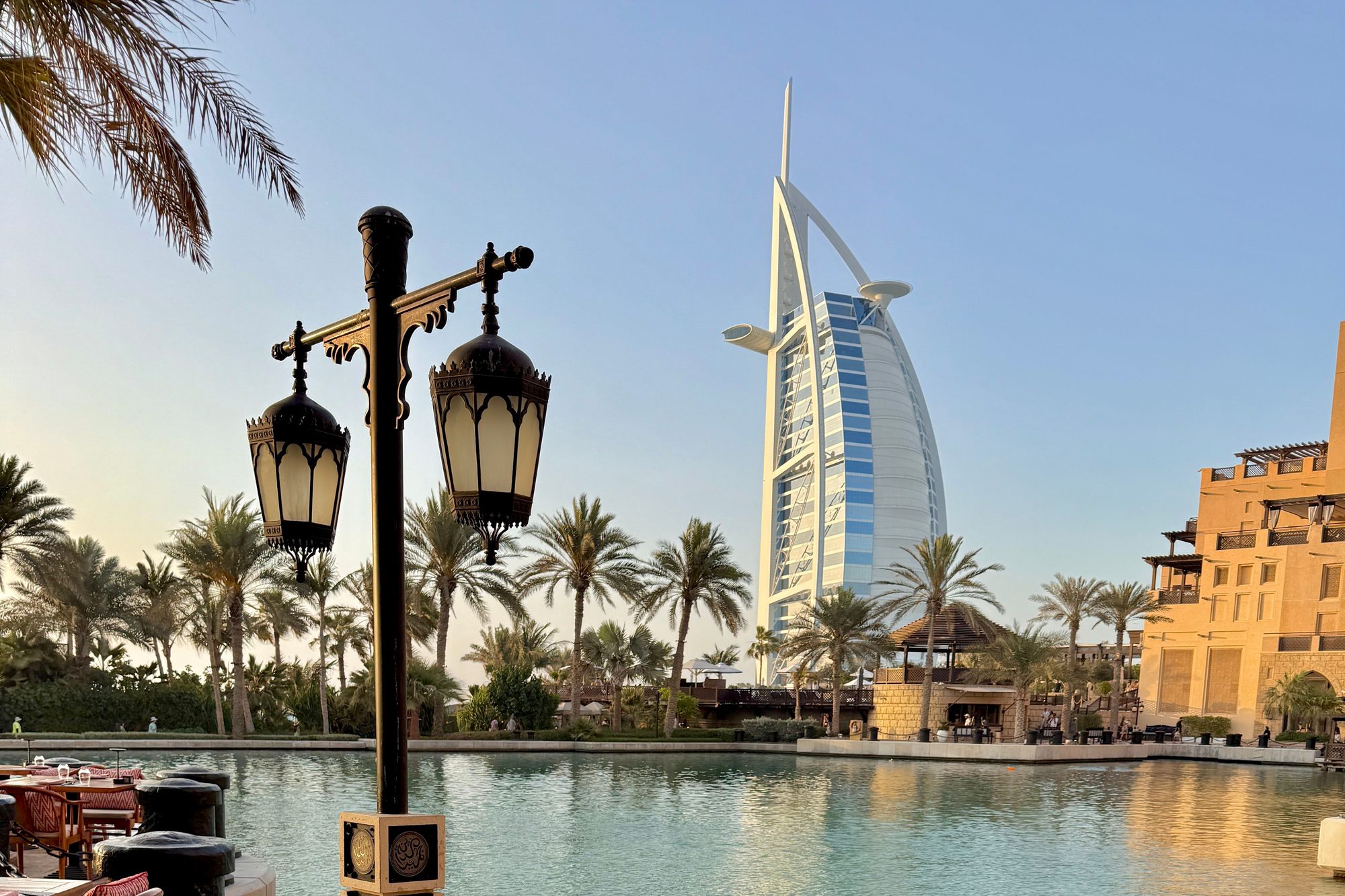 An elegant waterfront table with a view of the Burj Al Arab at golden hour in Dubai.