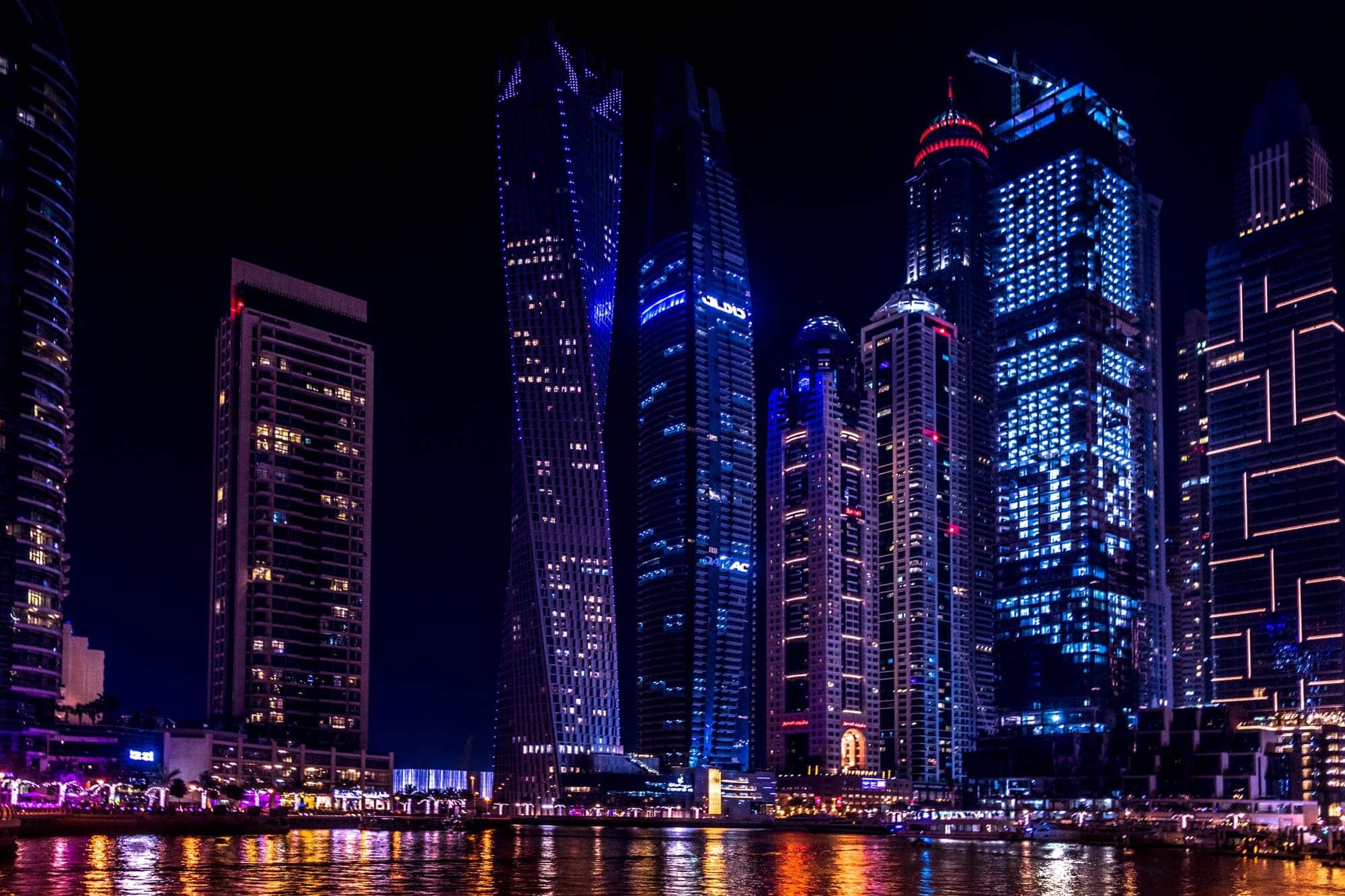 Dubai high-rise towers lit against a deep evening sky.