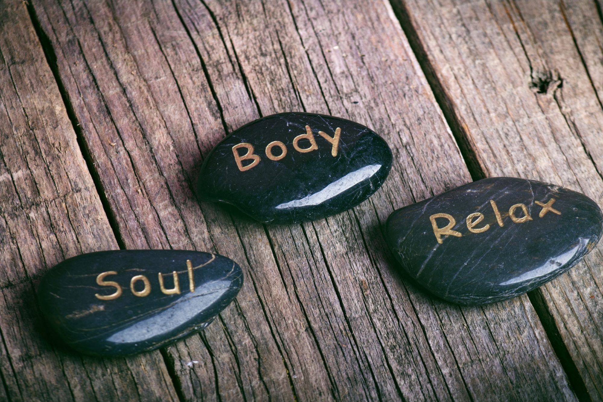 Spa stones inscribed soul, body and relax on wood, evoking calm wellness.